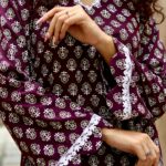 Close-up of a woman wearing a floral patterned dress with lace details outdoors.